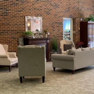 A cozy living room with sofas and chairs arranged around a central area, set against a brick wall.