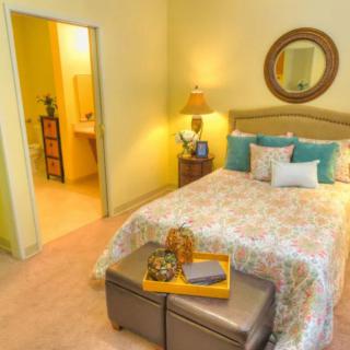 A cozy bedroom with colorful pillows and a decorative mirror.