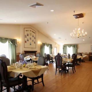 An elegant dining room with set tables, chandeliers, and decorative curtains.
