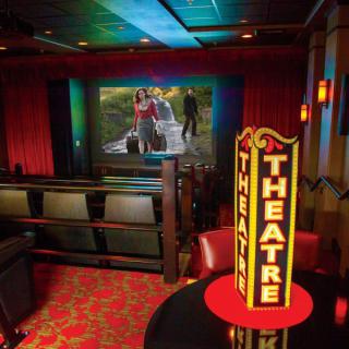 An intimate theater with plush seating and a large screen displaying a movie.