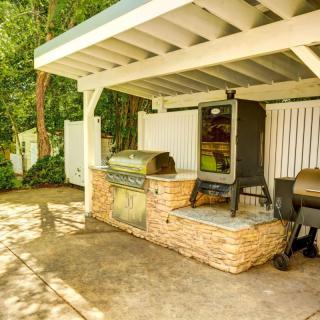 A covered outdoor kitchen area featuring a barbecue grill and smoker on a patio.