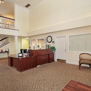 A spacious office reception area with a wooden desk and comfortable chairs.