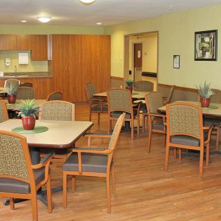 A cozy indoor dining area with tables and chairs, adjacent to a kitchen.
