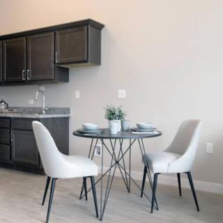 A modern kitchen with a minimalist dining area featuring a round table and two chairs.