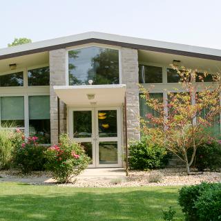 A modern residential building with large glass windows and well-maintained landscaping.