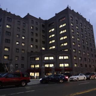 A dimly lit urban building with illuminated windows at dusk.