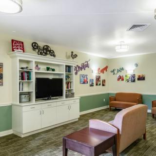 A cozy living room with a TV, sofas, and colorful wall decorations.