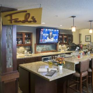 An inviting bar area with seating, a television, and a variety of drinks on display.