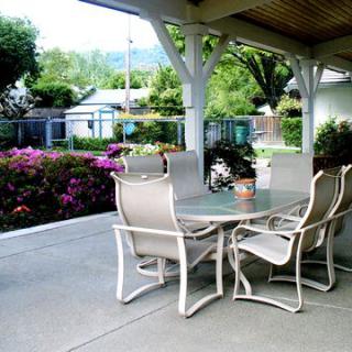 A covered patio with outdoor furniture surrounded by a garden.