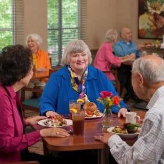 A group of seniors enjoying a meal together in a communal dining area.