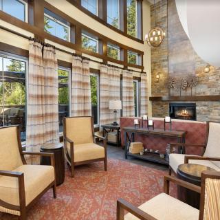 A beautifully designed living room featuring a cozy fireplace, elegant armchairs, and large windows with curtains allowing natural light.