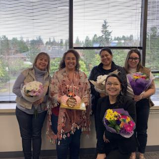 A joyful celebration with colleagues, surrounded by flowers and smiles.