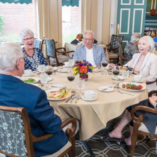 A group of elderly people enjoying a meal together at a dining table.