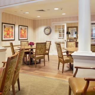 A cozy dining area with wooden chairs and tables, decorated with framed artwork on the walls.