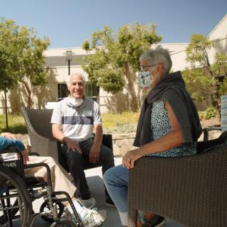 A group of seniors enjoying a conversation outdoors on a sunny day.