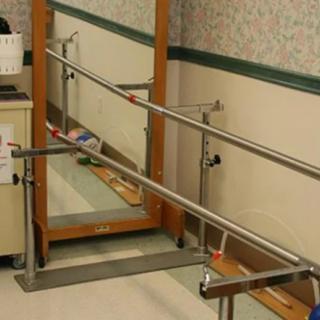 A clinical setting featuring parallel bars used for physical therapy and rehabilitation.