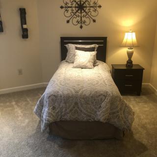A cozy bedroom with a single bed, nightstand, and warm lighting.