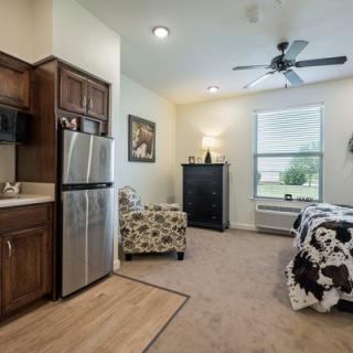 A cozy studio apartment featuring a kitchenette, bed, and seating area with modern furnishings.