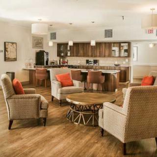 A cozy living room with a modern kitchen in the background, featuring comfortable seating and stylish decor.