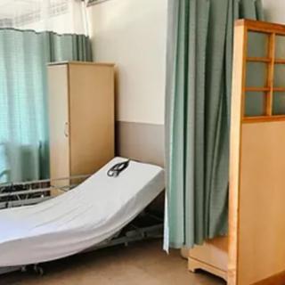 A hospital room with a bed, privacy curtains, and a cabinet.