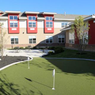 A modern building with a small outdoor putting green in the foreground.