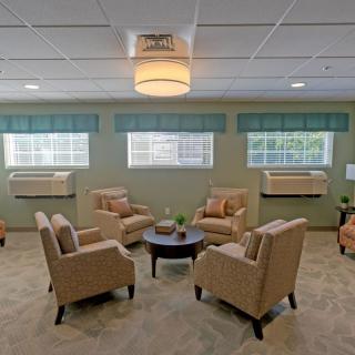 A cozy seating area with beige armchairs arranged around a circular table in a well-lit room.