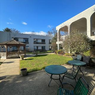 A serene courtyard featuring a gazebo and seating arrangements under a clear blue sky.