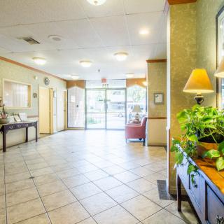 A bright lobby area with tiled floors, plants, and cozy furniture.