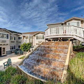 A modern apartment complex featuring a cascading water feature and outdoor seating area.