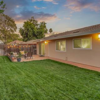 A serene backyard with a well-maintained lawn, cozy patio seating, and a beautiful sunset backdrop.