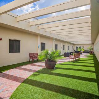 A well-maintained outdoor walkway with benches, potted plants, and a pergola overhead.