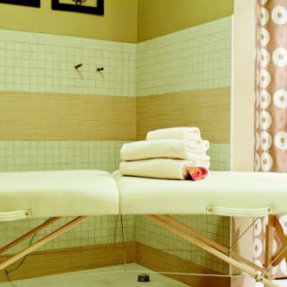 A serene spa room featuring a massage table with neatly folded towels.