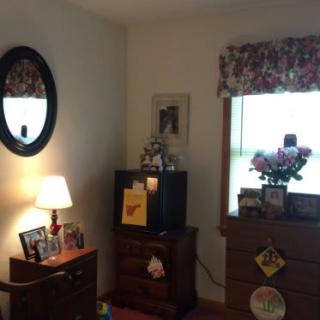 Cozy bedroom corner with a lamp, mirror, dresser, and television.