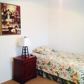 A cozy bedroom with a single bed and floral bedding, accompanied by a wooden nightstand and lamp.