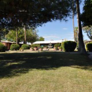 A suburban house with a well-maintained lawn and surrounding trees.
