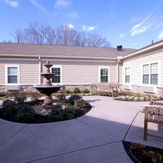 A serene courtyard with a central fountain, surrounded by benches and landscaped gardens.