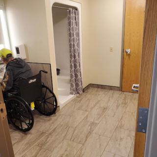 A spacious bathroom designed for accessibility, featuring a wheelchair and a shower area.