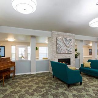 A cozy living room with teal sofas and a piano next to a fireplace.