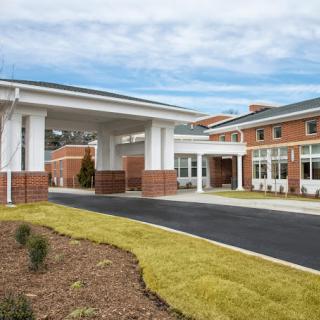 A modern building with a covered entrance and landscaped surroundings.