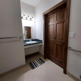 A view of a neatly designed bathroom featuring a sink, mirror, and wooden door.