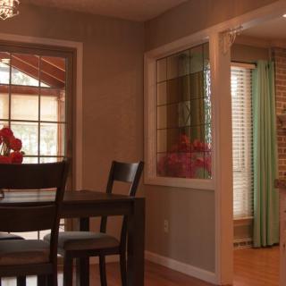 A cozy dining area with a dark wooden table and chairs, featuring large windows that let in natural light.