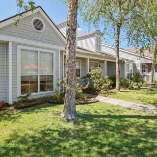 A charming residential house with a well-maintained lawn and surrounding trees.