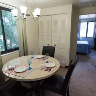 A cozy dining area set with plates and glasses, adjacent to a bedroom.