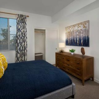 A modern bedroom with a stylish design featuring a bed, dresser, and decorative artwork.