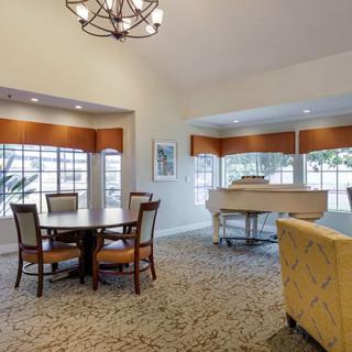 A spacious living room featuring a dining area, large windows, and a grand piano.