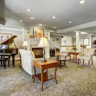 A cozy living room featuring a grand piano, comfortable seating, and a warm fireplace.