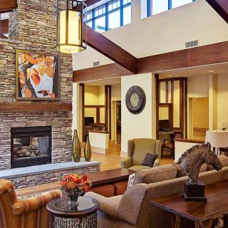 A stylish living room features a stone fireplace, elegant furniture, and modern decor with wooden beams.