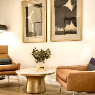 A modern living room with stylish armchairs, a round coffee table, and abstract artwork on the wall.