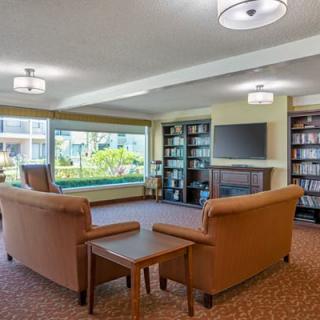 A cozy living room with sofas, bookshelves, and a large window overlooking a garden.