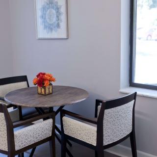 A cozy dining nook with a round table and chairs, adorned with a vase of flowers by the window.